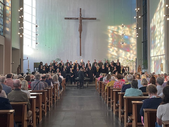 Bild: Chor singt in moderner, lichtdurchfluteter Kirche.